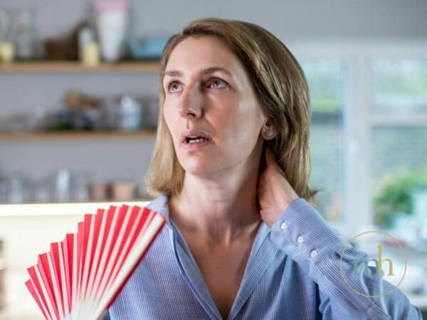 A woman utilizing a red fan for 5 menopause strategies.