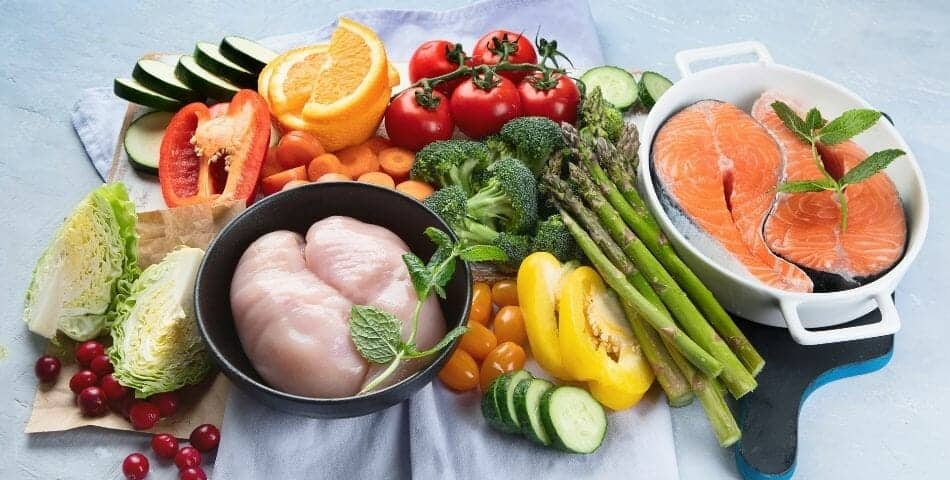 A variety of foods including salmon and vegetables are displayed on a blue background, promoting menopause nutrition foundations for a smooth journey.