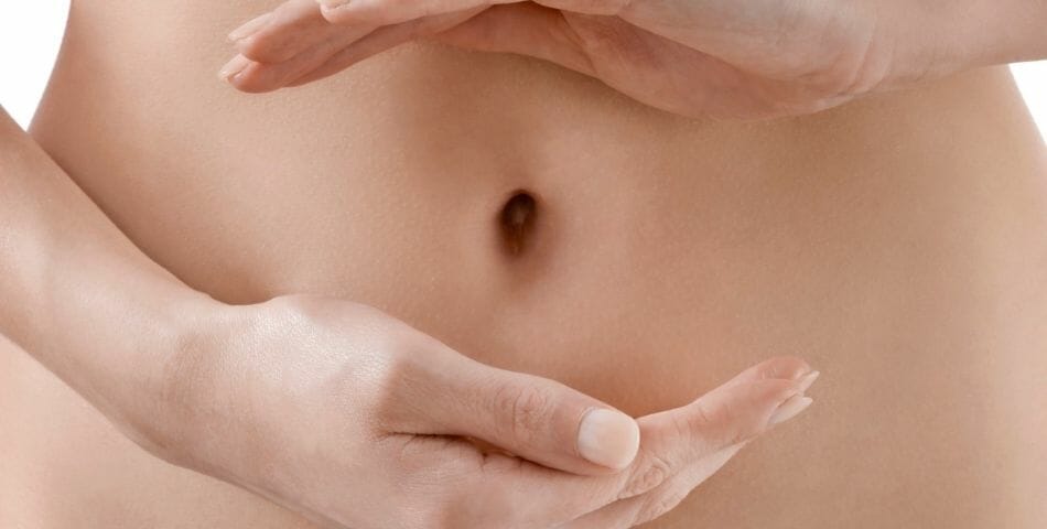 A woman demonstrates proper healthy digestion and weight loss by holding her stomach.