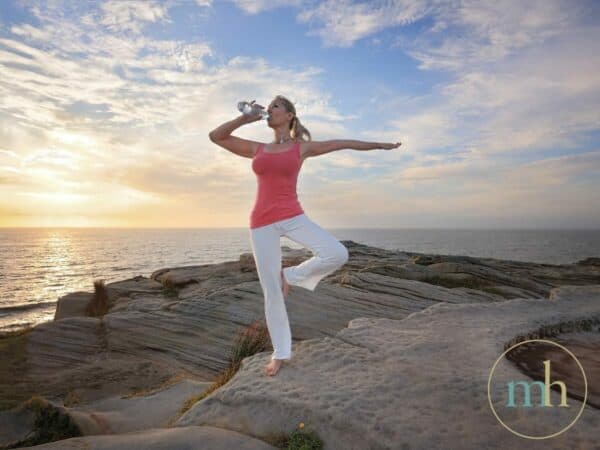A woman practicing yoga on a cliff, feeling amazing and overlooking the ocean.