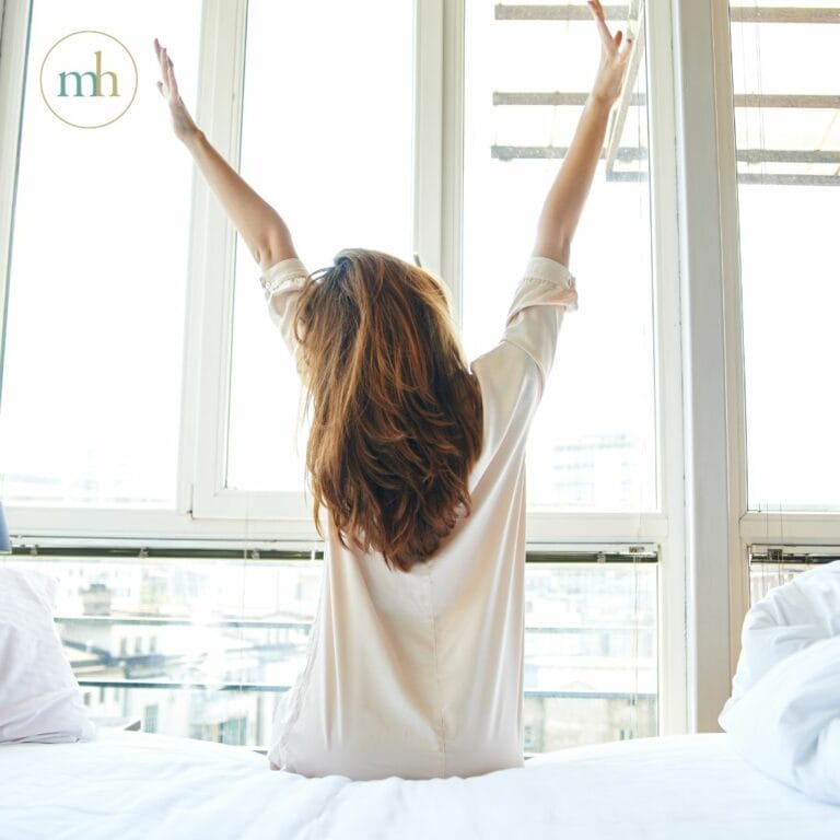 A woman is sitting on a bed with her arms raised in an Elementor Single Post.