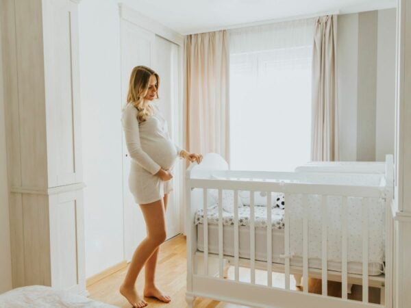 A pregnant woman employing the functional approach to preconception care poses beside a crib.